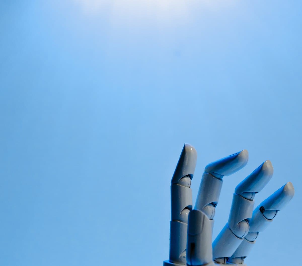 A robotic hand raised against a blue background
