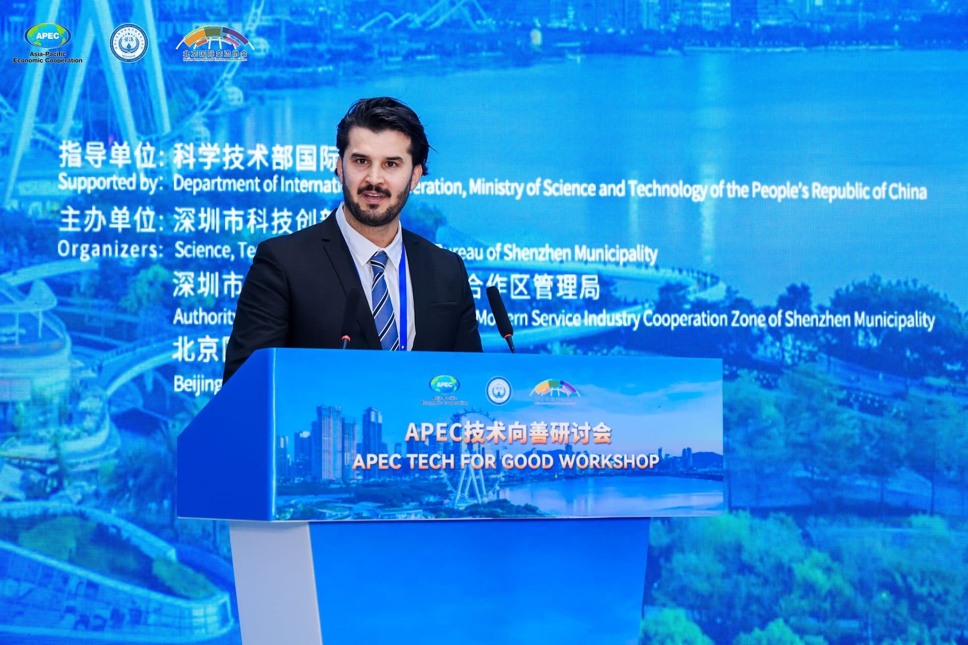 Syed Mosawi speaking at the APEC Tech for Good Workshop lectern in Shenzhen